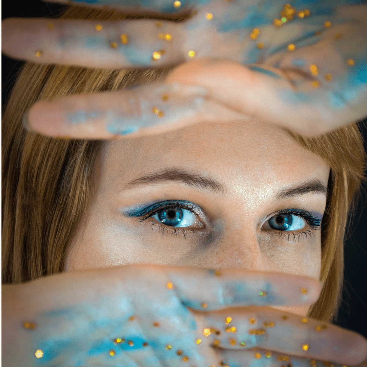 Nahaufnahme eines Gesichts mit glitzernder Hand